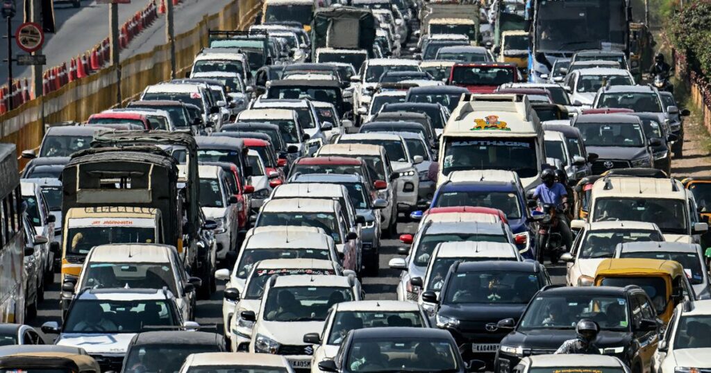A dense traffic jam in Bengaluru, with cars, buses, and motorbikes packed bumper-to-bumper, reflecting the city’s overpopulation, poor infrastructure, and urban planning challenges.