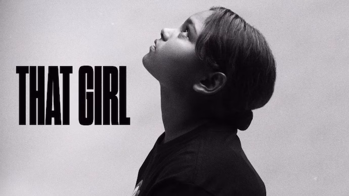 Black and white portrait of a young girl looking upward beside bold text that reads “THAT GIRL,” used as the official cover art for the song.